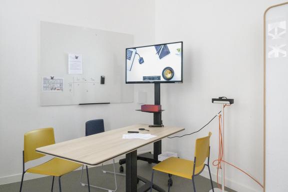 Les équipements du lab _ une table et 3 chaises devant u tableau 